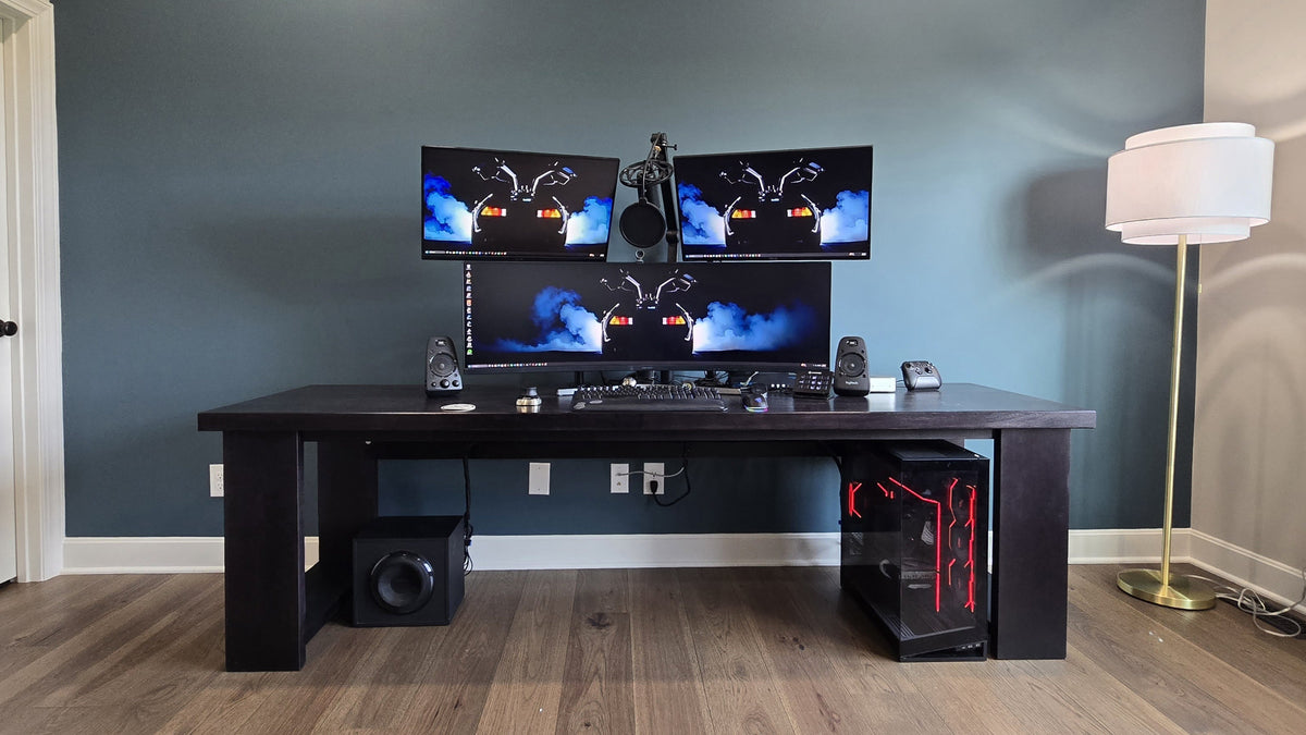 The finished Big Desk against a blue-gray wall, with three monitors on top and a PC tower under the right end